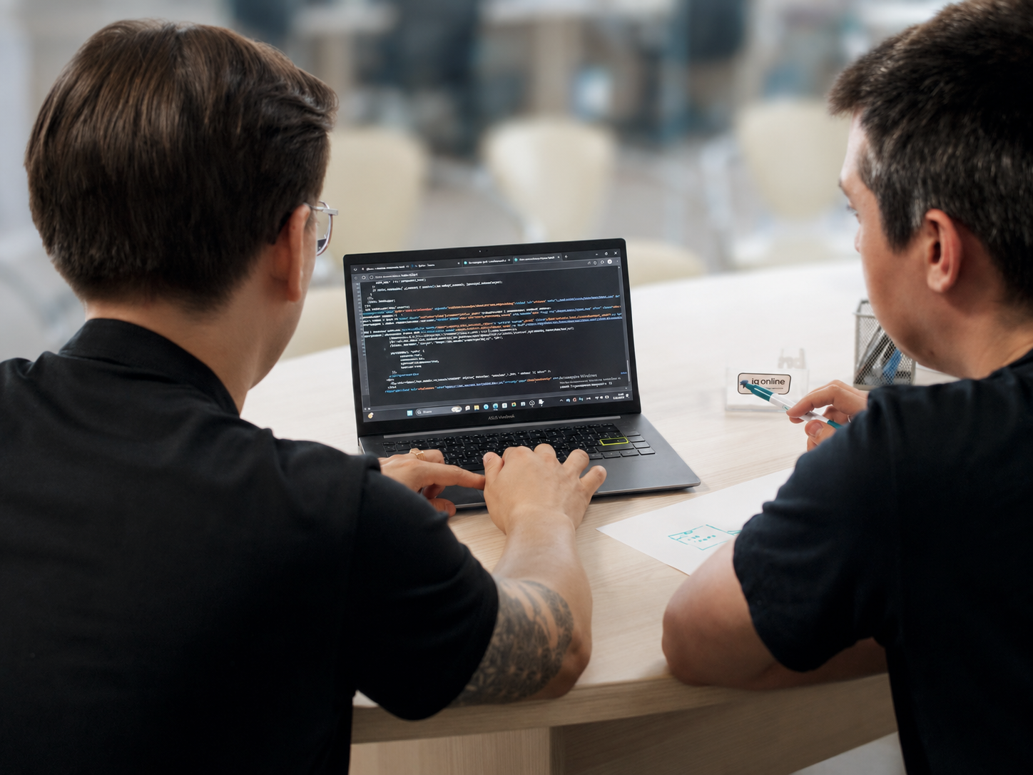 Двое разработчиков IQ Dev изучают код на экране ноутбука